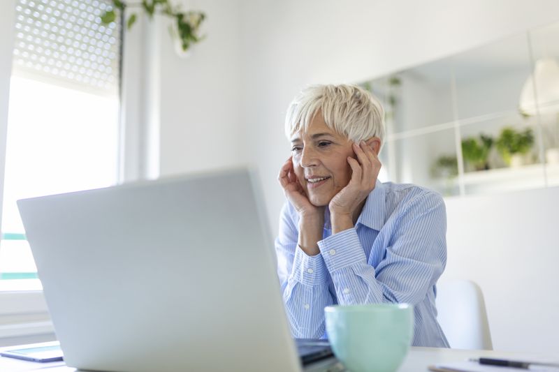 Una professionista sorridente lavora al portatile nel suo studio di casa