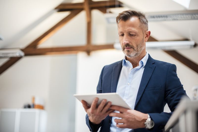 Un imprenditore consulta un report sul tablet in ufficio
